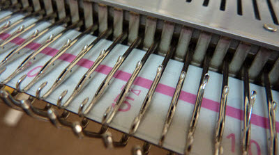 Are You Still a Beginner After 20 Years? Close-up view of a knitting machine's needle bed, showing the basic mechanical components of a knitting machine.