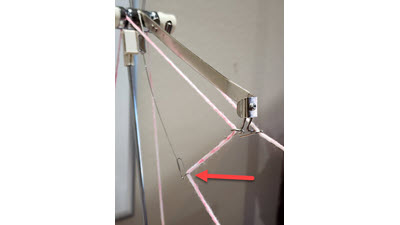 What's this wire? A metal sub-take-up spring attached to a Brother knitting machine's tension mast, used for adding tension during Fairisle and Thread Lace knitting
