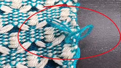 Loops at the edges A close-up photo showing loose, uneven loops along the edge of a knitted fabric, demonstrating a common knitting machine error