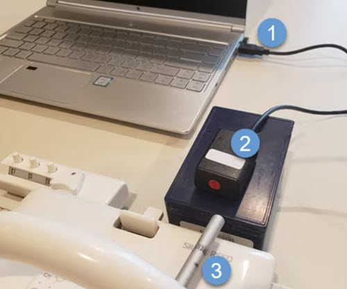 Laptop computer connected to an LK150 knitting machine with cables for DesignaKnit
