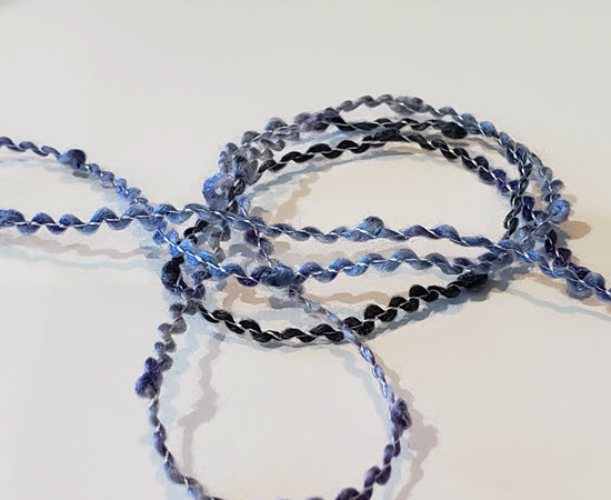 Bouclé yarn with textured loops created during the spinning process Bouclé textured yarn used in machine knitting